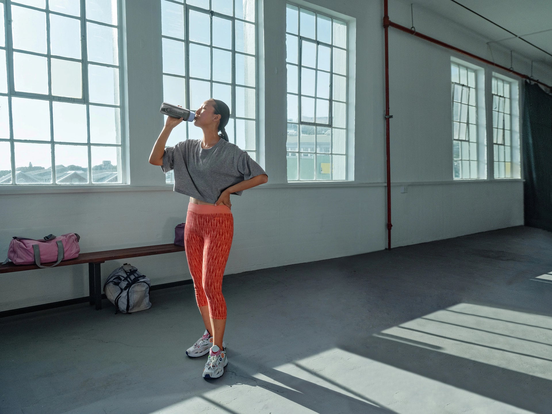 Person in athletic wear drinking from BRITA water filter bottle Model Active in a gym setting