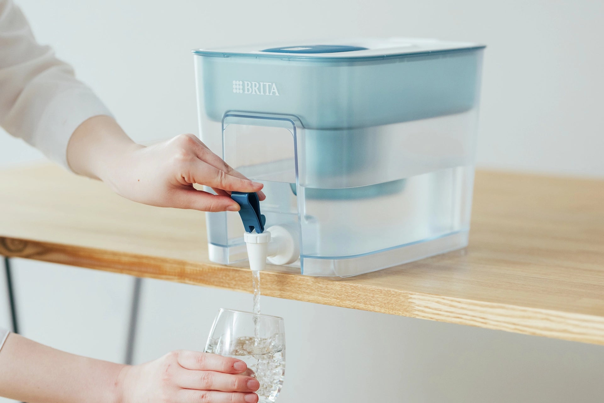 Person pouring water from a BRITA Flow into a glass.