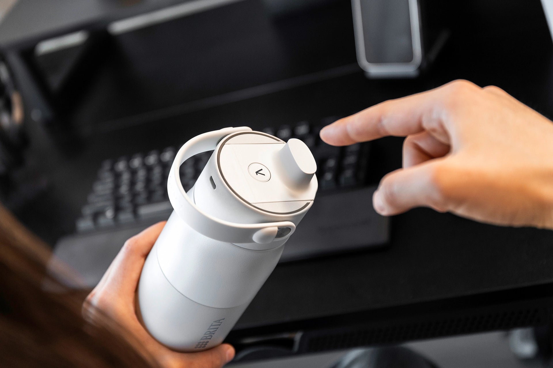 Close-up of a hand interacting with the touch button on a BRITA LARQ iQ Filter Bottle