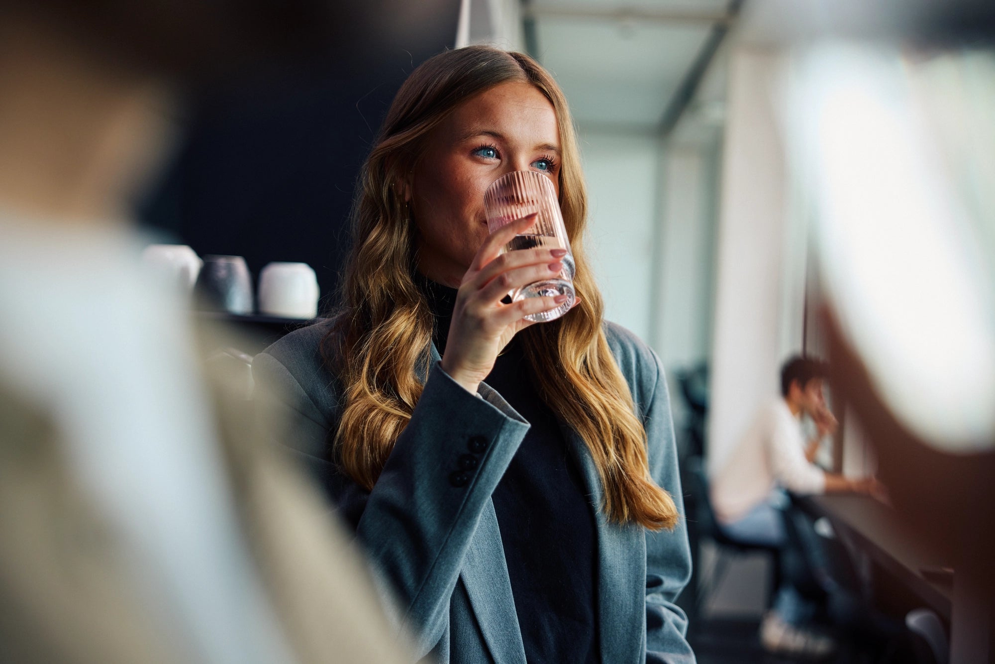 Woman drinking water in a modern office setting