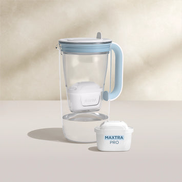 Un agua filtro Jarra de cristal con filtro en azul sobre fondo beige