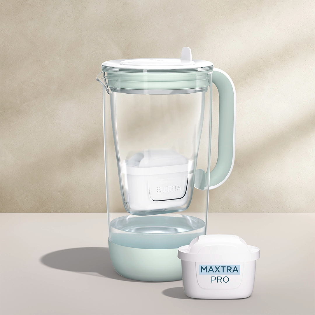 A water filter glass jug in green on a beige background