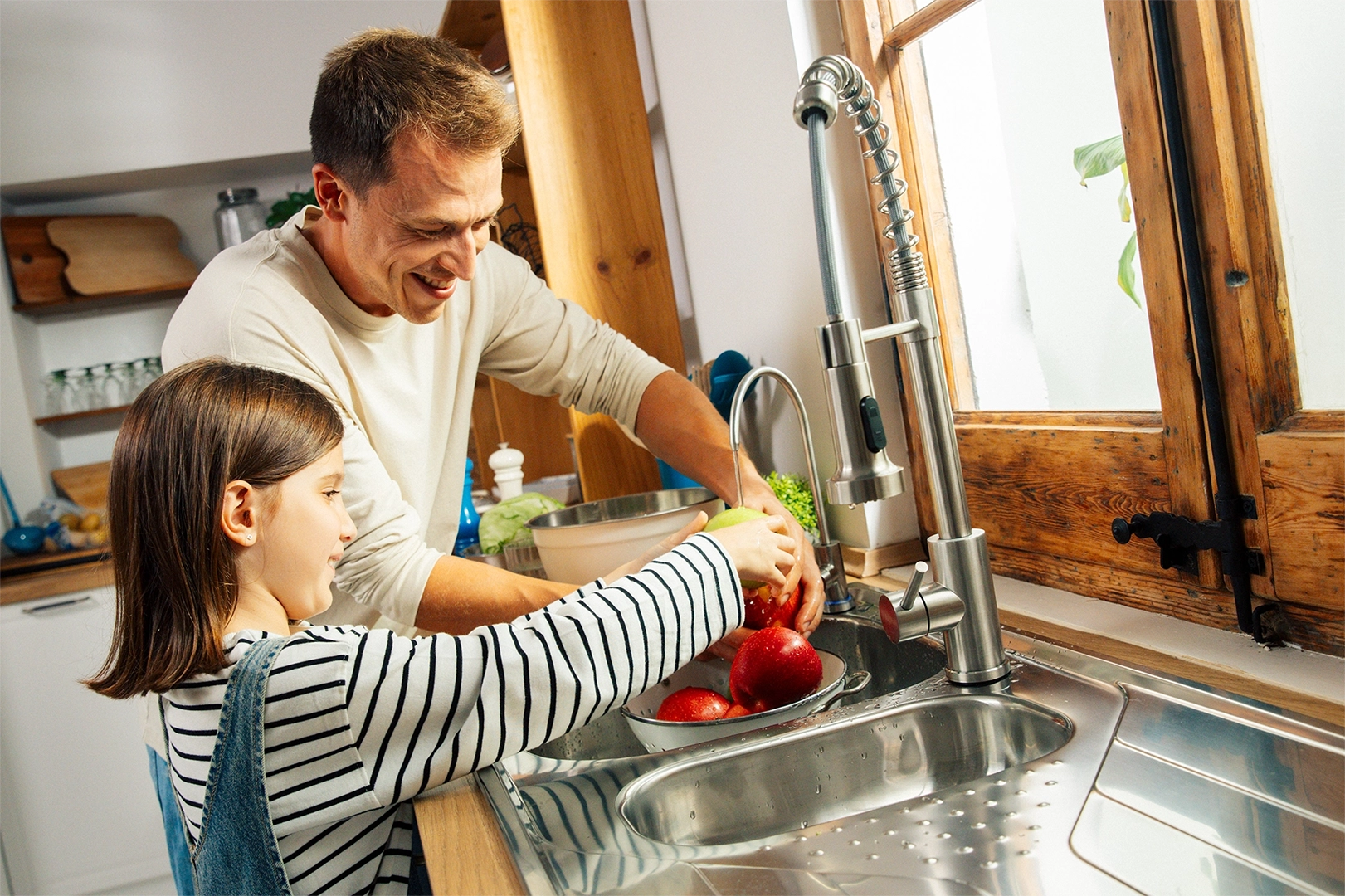 Man and young girl washing vegetables in a kitchen sink with mypure green ro water tap