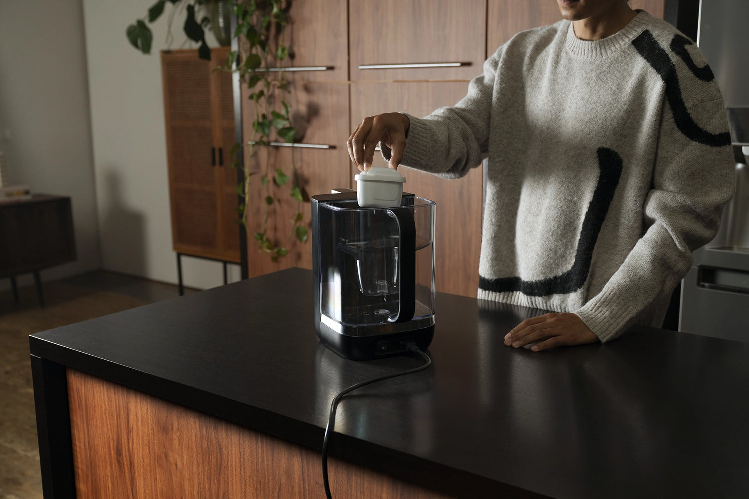 Person inserting a BRITA MAXTRA PRO filter cartridge into a BRITA YOURCE mini water dispenser.